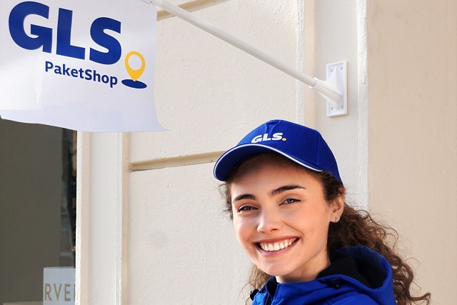 GLS Fahrerin steht vor einer GLS PaketShop Fahne