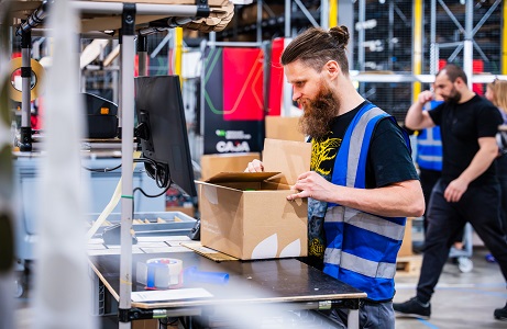 Fulfillment Mitarbeiter komissioniert gerade ein Paket